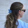 Girl wearing the blue butterfly hair claw in a half-up half-down hairstyle. She is wearing sunglasses and a white t-shirt