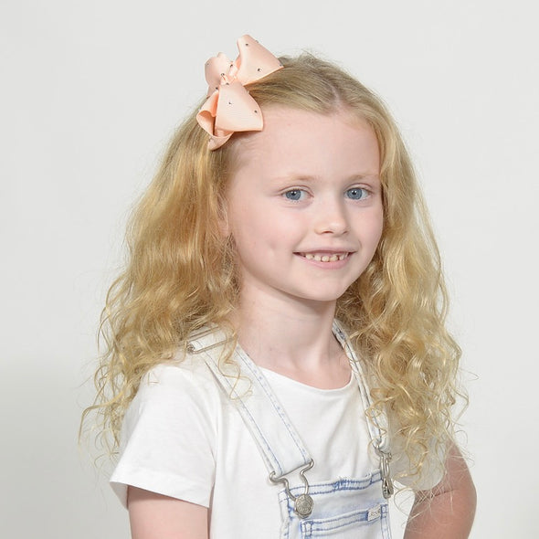 Girl wearing light apricot diamante hair bow.