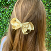 Girl wearing gold ribbon bow. Size: 100mm x 60mm (approx. 3 1/2 inches) Ribbon width: 25 mm.