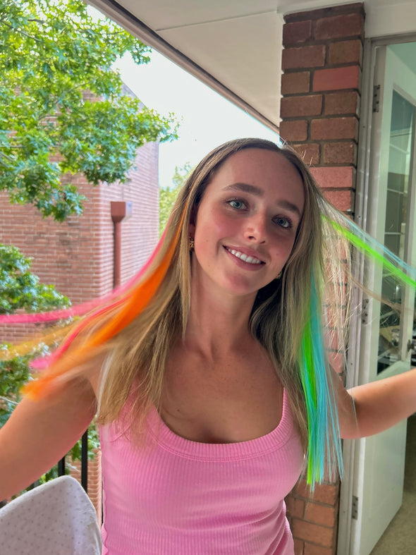 Girl wearing hair extensions in a variety of colours - orange, pink, blue, green and yellow.