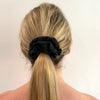 Blonde lady wearing Black - Lexi Scrunchie. Material: Cotton Polyester blend. Dimensions: Material width approximately 4cm. Made by us in Bondi Beach.