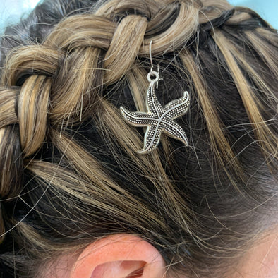 Starfish charm/hair charm in silver colour (hook included). Our silver starfish hair charm is hooked onto a thin malleable metal wire for easy use and ultimate comfort!  Dimensions: 22mm x 22mm.  Material: Charm - zinc alloy, lead free. Hooks - surgical steel.