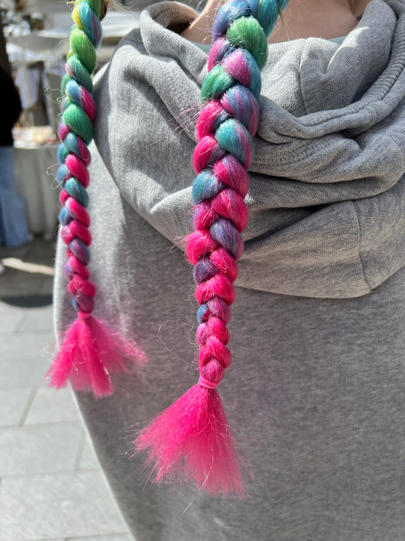 Girl wearing jumbo hair braid in pink rainbow.