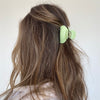 Girl wearing mini hair claw in green.