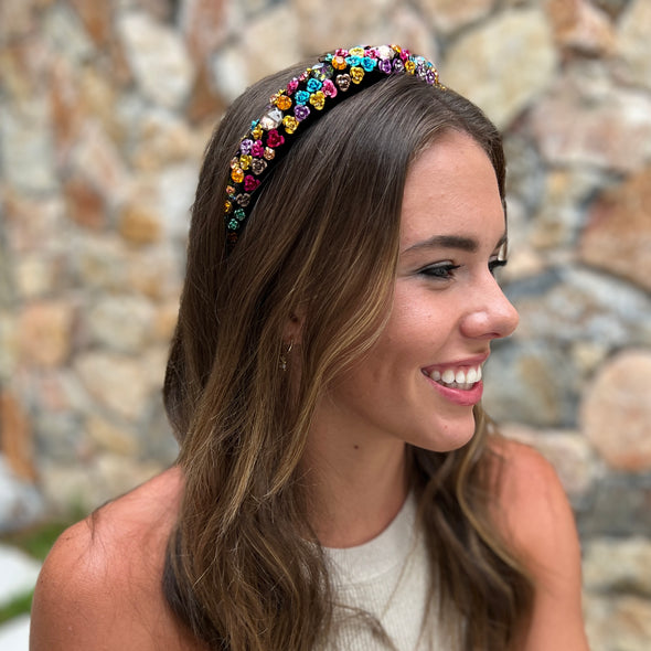Girl wearing headband on a black base with blue, pink, purple and yellow flower diamantes.