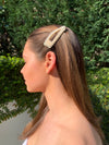 Girl wearing large pearl hair triangle shaped hair clip with gold coloured setting.