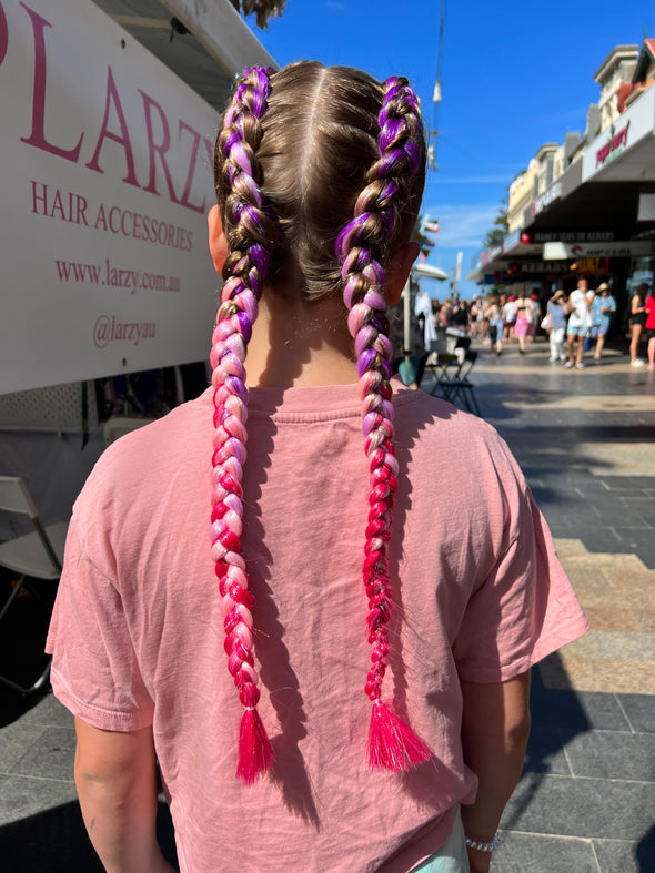 Girl wearing jumbo hair braid in purple, lilac, pale pink and pink with tinsel.