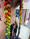 Girl wearing jumbo hair braid in rainbow.