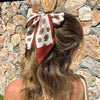 Girl wearing autumn tone floral hair scarf on cream fabric with auburn/brown edging.