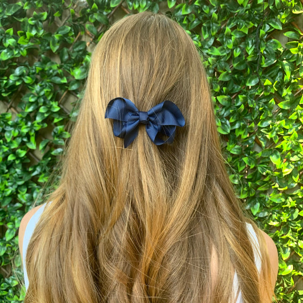 Girl wearing navy hair bow.