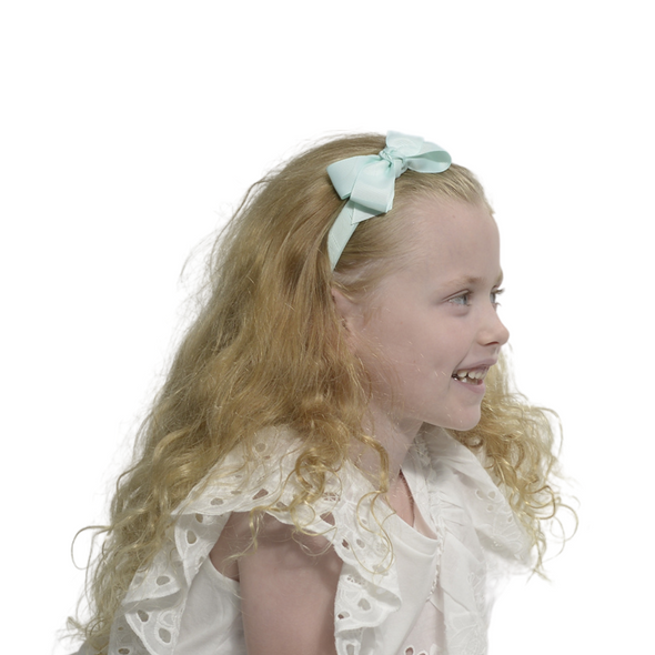 Girl wearing spearmint coloured headband with bow.