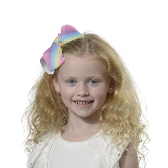 Girl wearing large rainbow clip in bow.